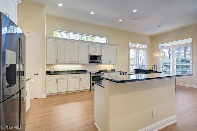 kitchen with pendant lighting, white cabinets, light hardwood / wood-style flooring, appliances with stainless steel finishes, and a chandelier