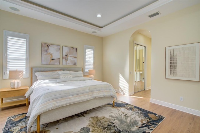 bedroom featuring a raised ceiling and light hardwood / wood-style flooring