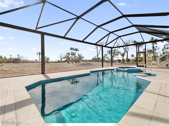 view of pool with glass enclosure, a patio area, and an in ground hot tub