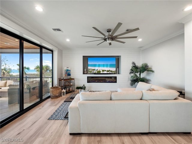 living room featuring ceiling fan, crown molding, and light hardwood / wood-style flooring