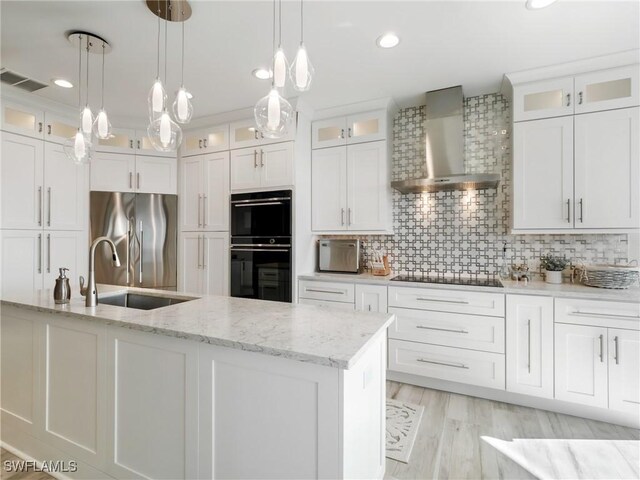 kitchen with tasteful backsplash, white cabinetry, wall chimney exhaust hood, and black appliances