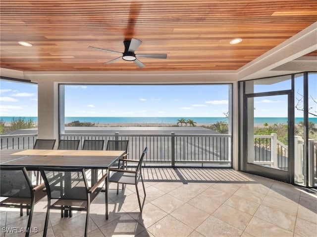 unfurnished sunroom featuring ceiling fan, a water view, plenty of natural light, and wood ceiling