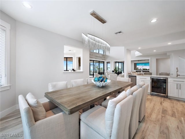 dining area featuring sink, beverage cooler, and light hardwood / wood-style flooring