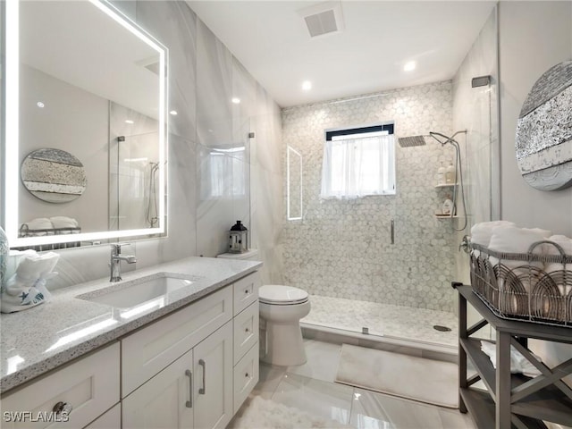 bathroom featuring tile patterned flooring, vanity, toilet, and a shower with shower door