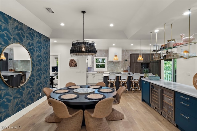 dining room featuring light wood-style floors, beverage cooler, and wallpapered walls