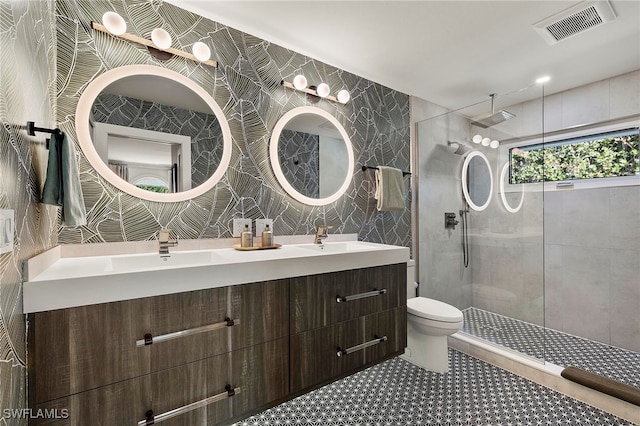 bathroom with visible vents, tile walls, toilet, walk in shower, and a sink