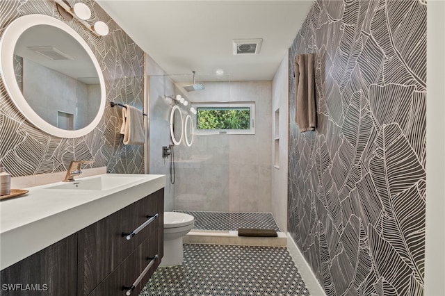 full bath with tile walls, visible vents, toilet, a tile shower, and vanity