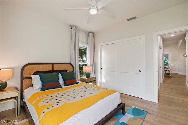 bedroom with a closet, wood finished floors, visible vents, and baseboards