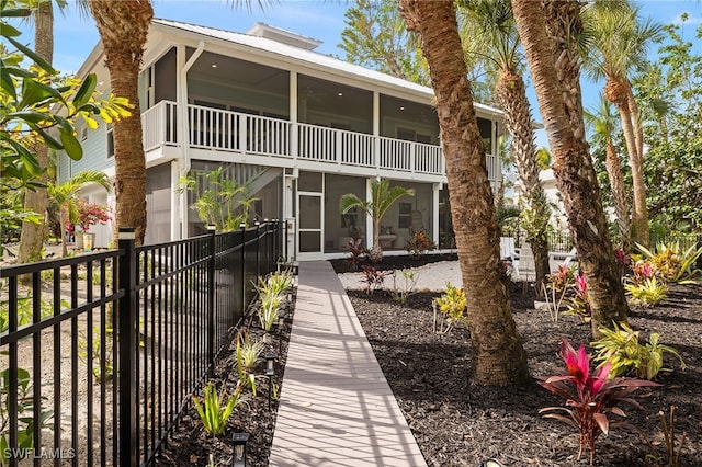 rear view of house featuring a sunroom and fence