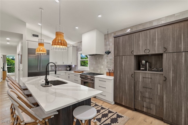 kitchen with high end appliances, a sink, visible vents, and a kitchen breakfast bar