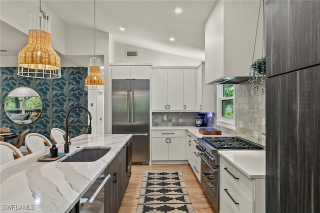 kitchen with visible vents, premium appliances, vaulted ceiling, light wood-type flooring, and a sink