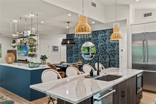 kitchen featuring appliances with stainless steel finishes, an island with sink, visible vents, and light wood-style floors