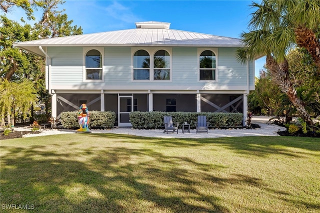 rear view of property with metal roof and a lawn