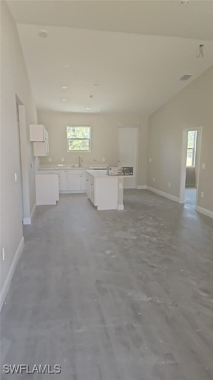 3019 32nd St W, Lehigh Acres, FL 33971 - unfurnished living room with concrete floors, baseboards, lofted ceiling, and a sink