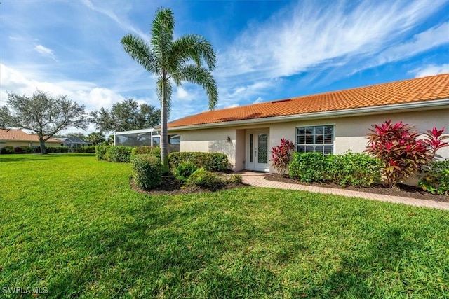 back of house with a lanai and a yard