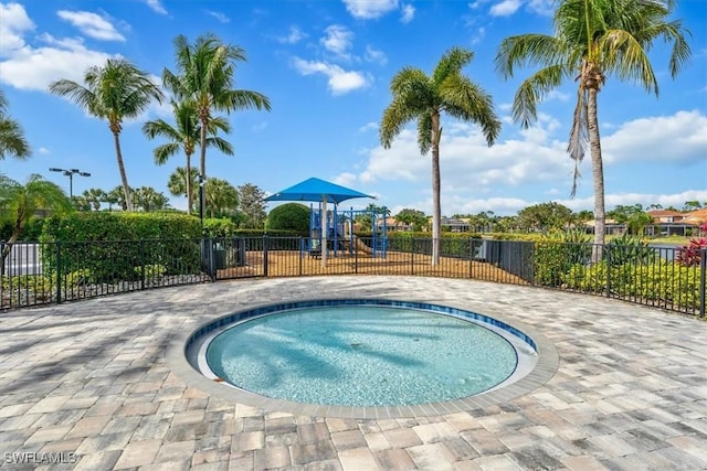 view of swimming pool with a playground and an in ground hot tub