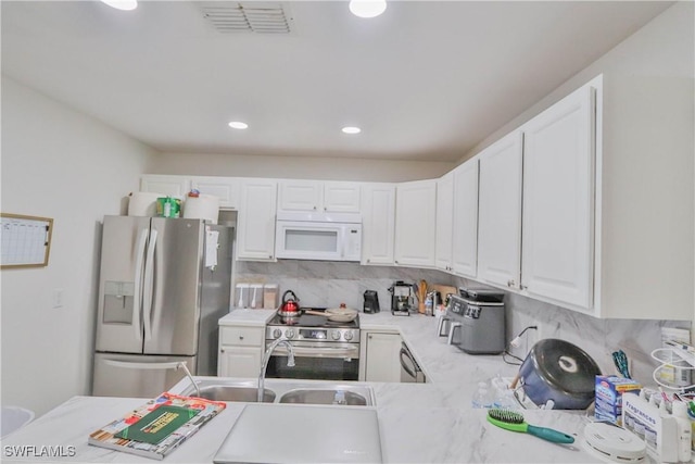 kitchen featuring kitchen peninsula, appliances with stainless steel finishes, tasteful backsplash, sink, and white cabinets