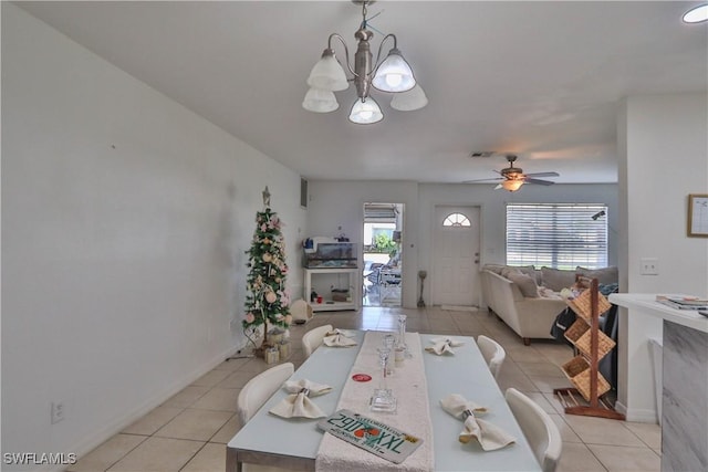 tiled dining area with ceiling fan with notable chandelier