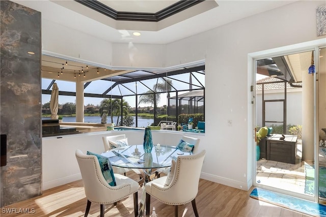 sunroom / solarium with a raised ceiling, plenty of natural light, and a water view