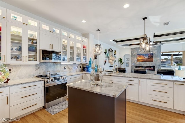 kitchen featuring white cabinetry, stainless steel appliances, light stone counters, backsplash, and a kitchen island