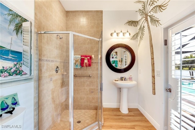 bathroom featuring sink, a shower with door, wood-type flooring, and toilet