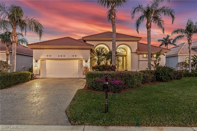 mediterranean / spanish-style home featuring a garage and a yard