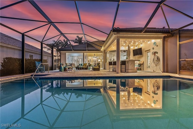 pool at dusk featuring a lanai, an outdoor pool, and a patio