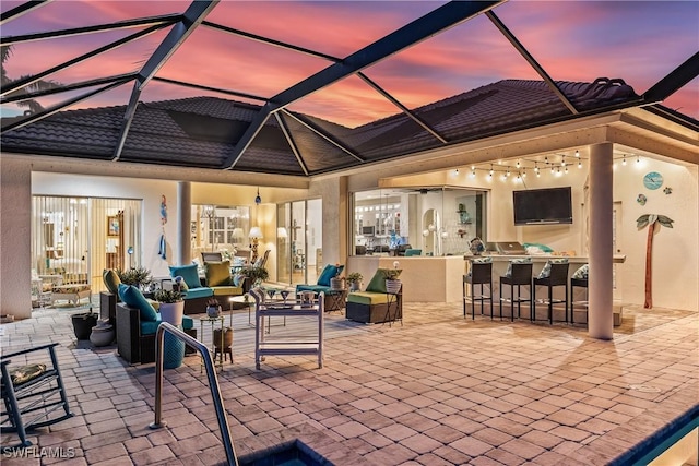 view of patio / terrace with glass enclosure, area for grilling, and exterior bar