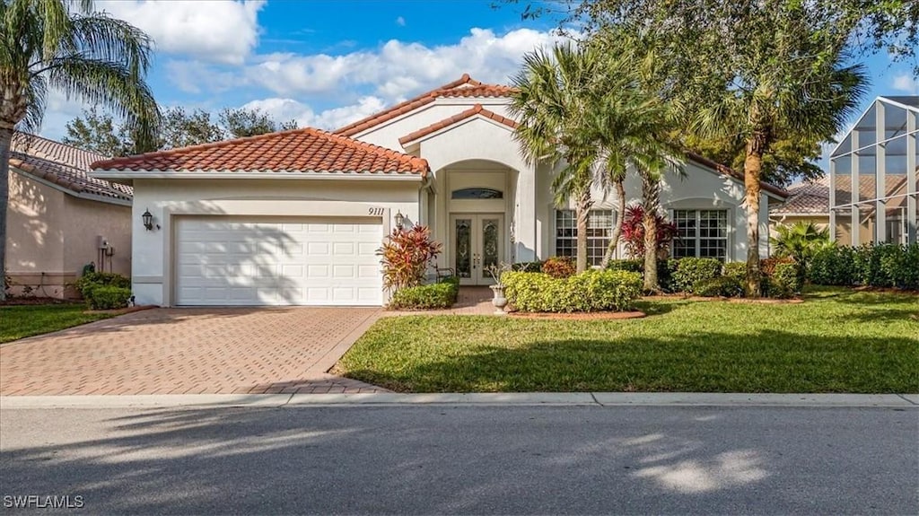 mediterranean / spanish home with french doors, a front lawn, and a garage