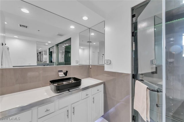 bathroom featuring vanity, an enclosed shower, and tile walls