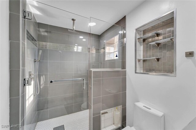 bathroom with a shower with door and toilet