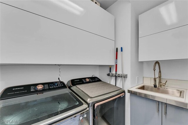 laundry room with washer and clothes dryer, sink, and cabinets