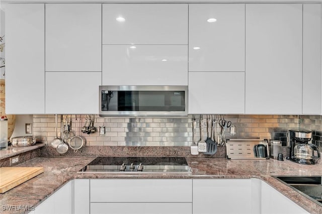 kitchen with white cabinets, decorative backsplash, stone countertops, and black electric stovetop