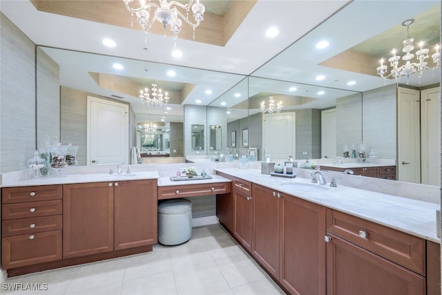 bathroom with tile patterned floors, a raised ceiling, vanity, and a notable chandelier