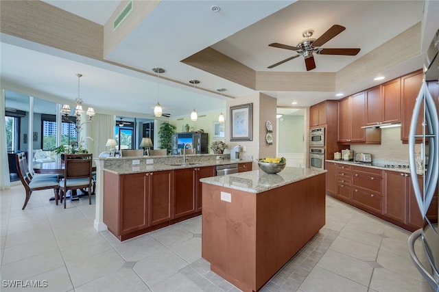 kitchen featuring hanging light fixtures, a raised ceiling, kitchen peninsula, and a kitchen island