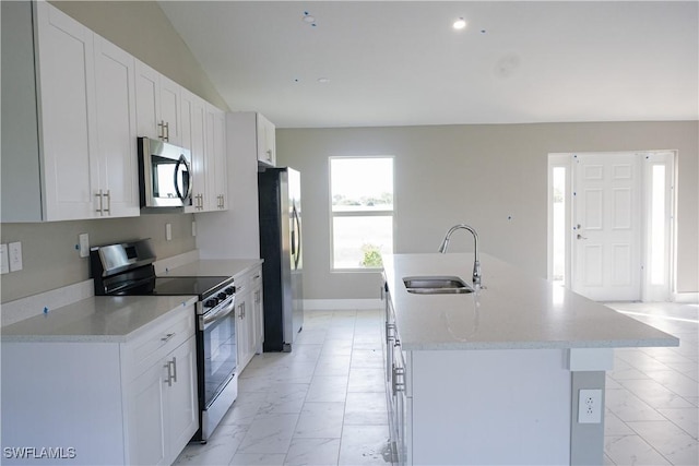 kitchen with white cabinetry, sink, a kitchen island with sink, stainless steel appliances, and light stone countertops