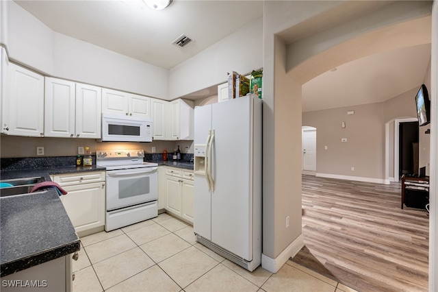 kitchen with white cabinetry, sink, light tile patterned flooring, and white appliances