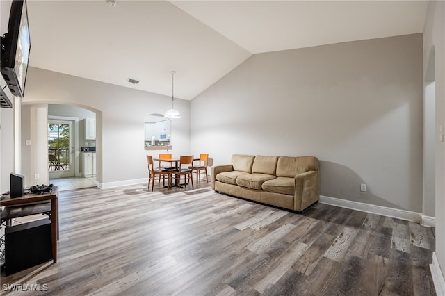 living room with arched walkways, visible vents, baseboards, and wood finished floors