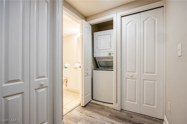 laundry area featuring stacked washer / drying machine and light hardwood / wood-style floors