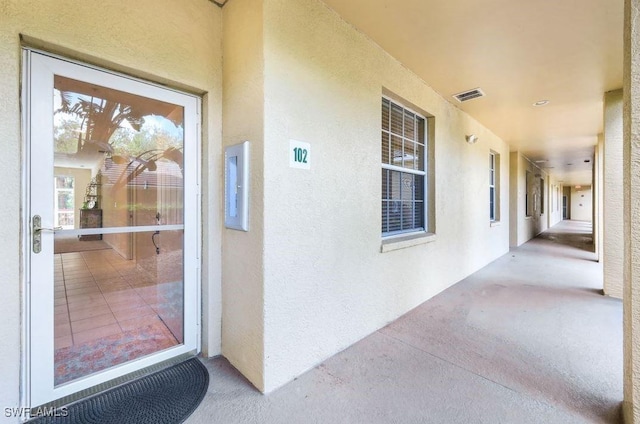 view of exterior entry with visible vents and stucco siding