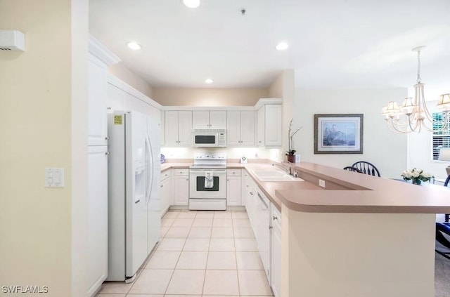 kitchen featuring a peninsula, a notable chandelier, white cabinets, white appliances, and a sink