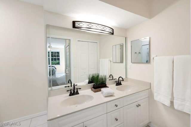 bathroom featuring a sink, baseboards, double vanity, and tile patterned floors