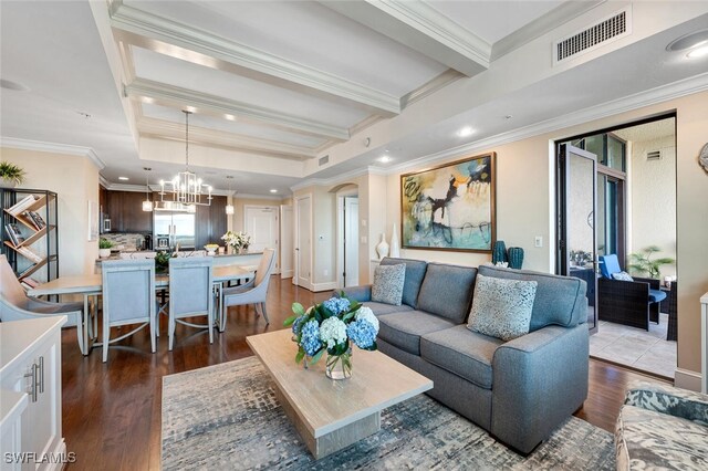 living room featuring beamed ceiling, wood-type flooring, ornamental molding, and a notable chandelier