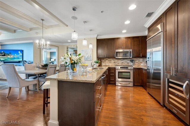 kitchen with sink, light stone counters, hanging light fixtures, appliances with stainless steel finishes, and kitchen peninsula