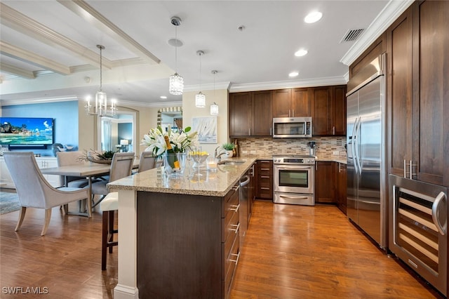 kitchen featuring appliances with stainless steel finishes, beverage cooler, a sink, ornamental molding, and dark wood-style floors
