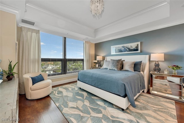 bedroom with ornamental molding, wood-type flooring, and a tray ceiling