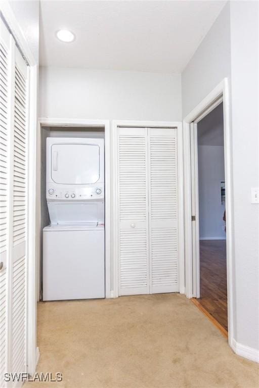 clothes washing area featuring light carpet and stacked washer / drying machine