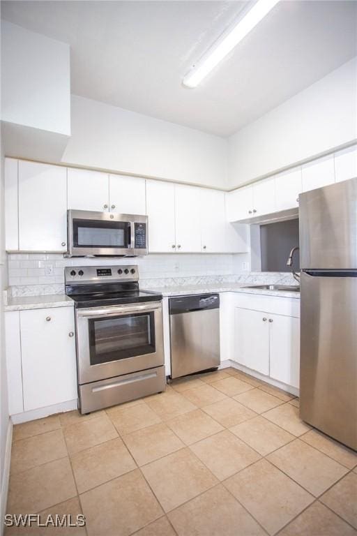 kitchen featuring light tile patterned flooring, white cabinetry, sink, and appliances with stainless steel finishes