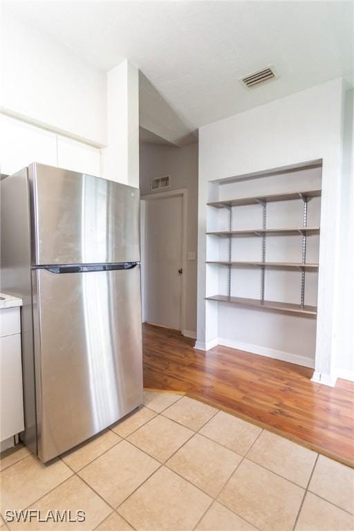 kitchen with light tile patterned floors and stainless steel refrigerator