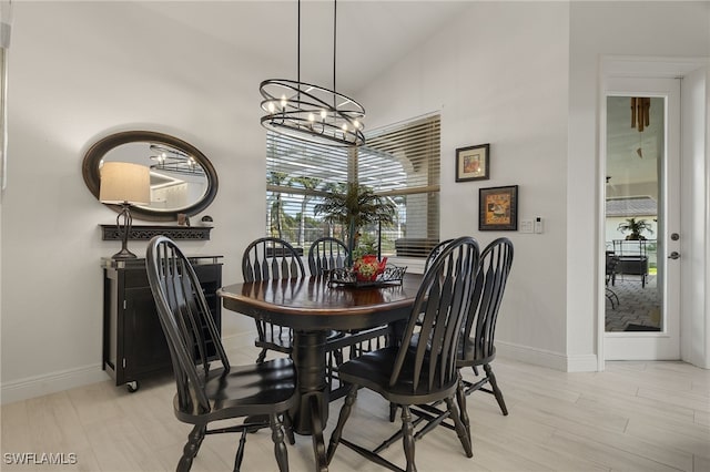 dining area featuring light hardwood / wood-style flooring, lofted ceiling, and an inviting chandelier